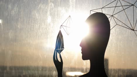 silueta de una persona sosteniendo una forma de diamante, con patrones geométricos y vista del atardecer a través de la ventana