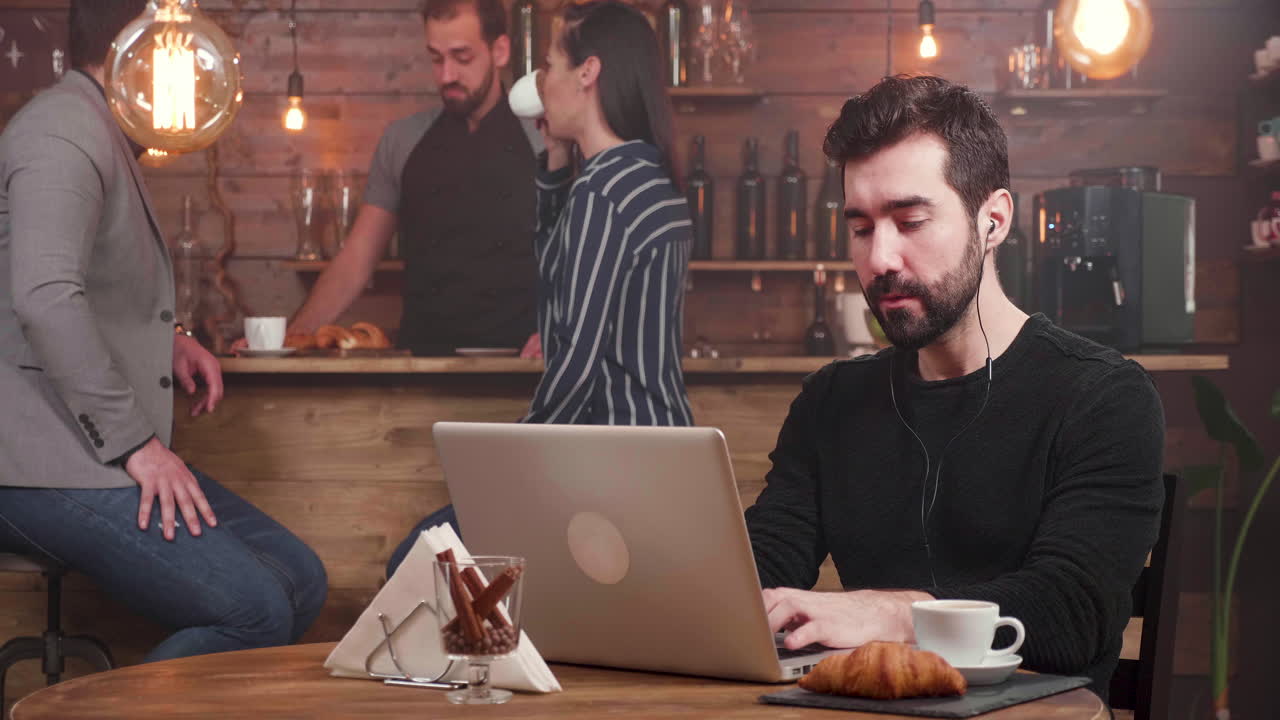 Man working on laptop in a cafe with other people