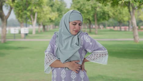 muslim woman suffering from back pain in park