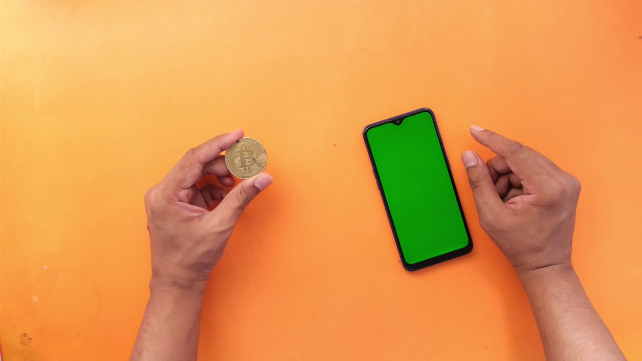 오렌지색 표면에 비트코인 및 휴대 전화