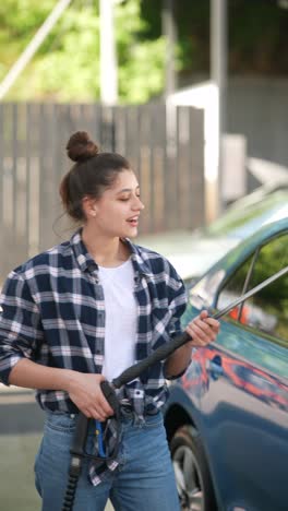 teenage girl washing a car at a self-service car wash