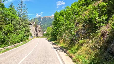 mountain road with lush greenery and old buildings