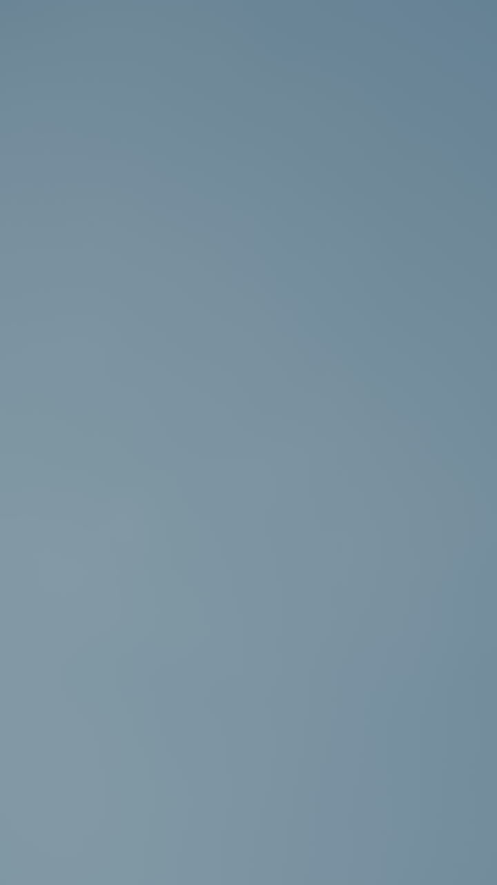 vista hacia arriba de un hombre preparándose para servir voleibol bajo un cielo brillante y despejado, centrarse en las manos y la pelota, enfatizando la acción de voleibol en un entorno al aire libre con tiempo soleado