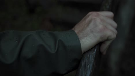 a close-up shot of a man's hand firmly grasping a wooden railing