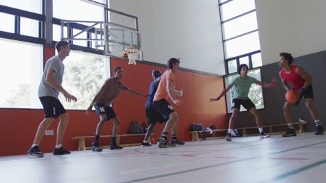 Diverse-male-basketball-team-and-coach-playing-match