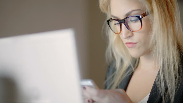 Businesswoman Using Smartphone And Looking At Finance Data On Laptop 1