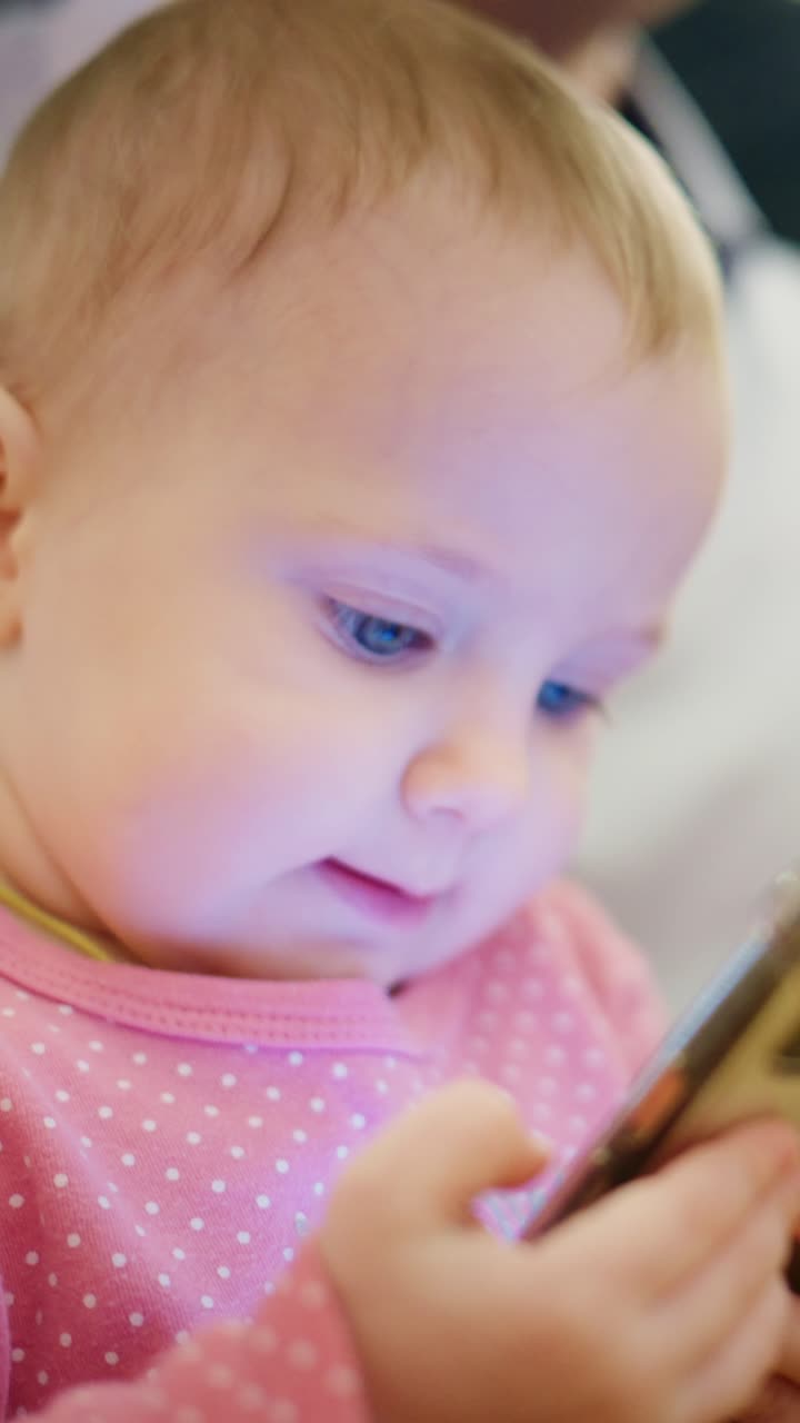 幼い頃からテクノロジーに触れ、明るい色彩と魅力的なコンテンツを楽しみながら、モバイル画面に夢中になっている赤ちゃん