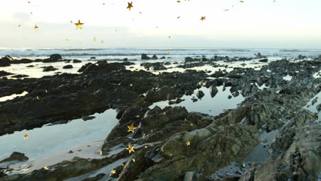 jagged rocky shoreline revealing tide pools reflecting water while golden confetti floating