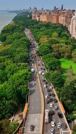 Two side freeway along the green area at Hudson river waterfront. Busy traffic on the roads of New York at day. Top view. Vertical video