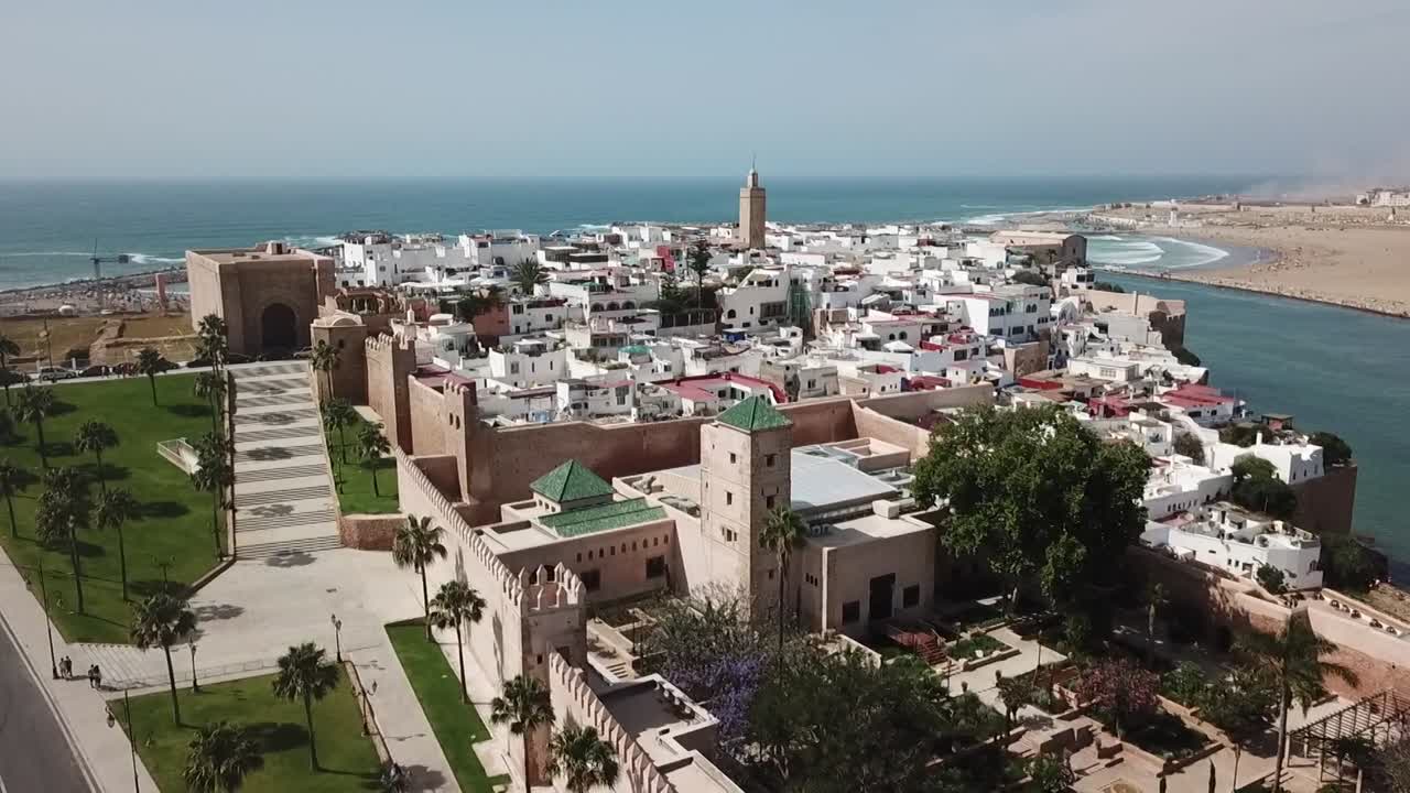 Naturskønt dronebillede af den historiske Kasbah af Udayas. Viser fæstningsmurene, traditionelle hvide huse, Andalusiske haver og Bou Regreg-floden, der løber ud i Atlanten.