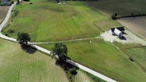 RC-Plane-Flying-Over-Narrow-Road-Between-Agricultural-Land-On-A-Sunny-Summer-Day