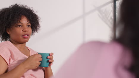 group of women meeting around table and talking at therapy support group for breast cancer treatment patients