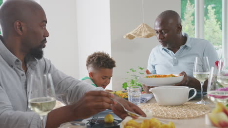 grandfather with father and grandson enjoying multi-generation family meal at home
