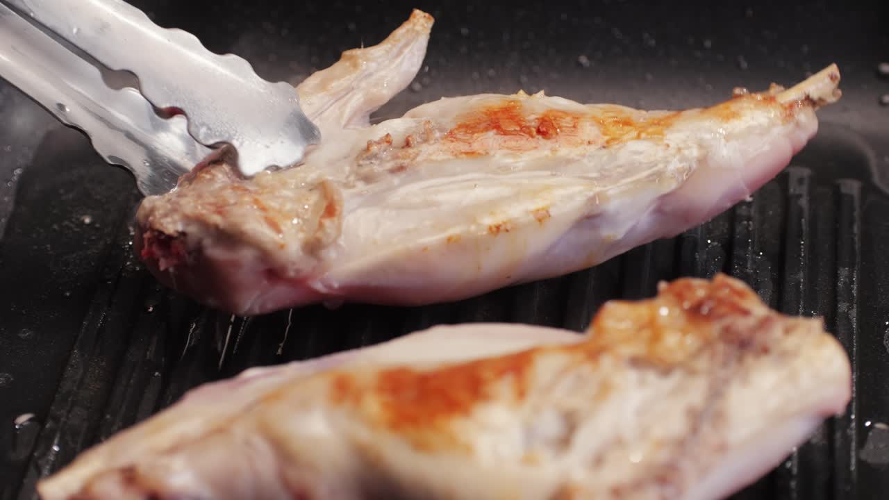 Roasted rabbit legs in a grill pan, healthy diet meat close up, chef cooking rabbit on kitchen restaurant, Black background. Top view