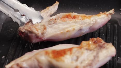 roasted rabbit legs in a grill pan, healthy diet meat close up, chef cooking rabbit on kitchen restaurant, black background. top view
