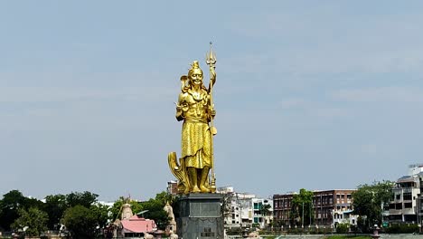 stunning aerial of golden lord shiva statue at sursagar lake, vadodara, gujarat—sacred hindu icon in urban setting.