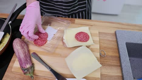 Person preparing a salami and cheese sandwich in the kitchen