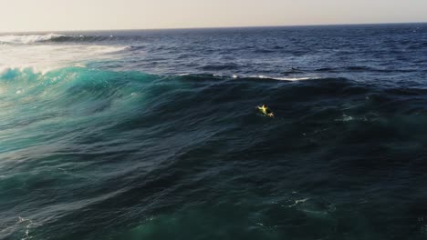 Lonely-surfer-swimming-towards-massive-ocean-waves,-aerial-view