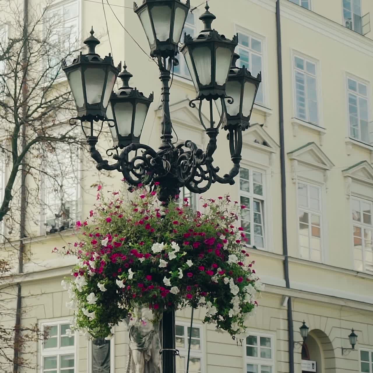 decorative lantern is located in the center of city on the background of urban architecture. Camera motion up