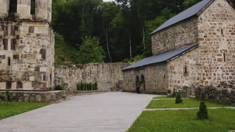 Frau-Bekreuzigt-Sich-Im-Innenhof-Des-Mtsvane-Klosters-Und-Betritt-Die-Kirche