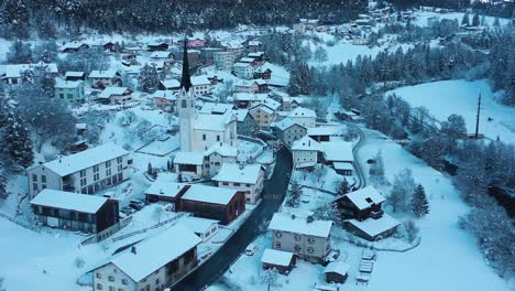 Excelente-Vista-Aérea-De-Un-Automóvil-Que-Pasa-Por-Una-Capilla-En-Filisur-Invernal,-Suiza