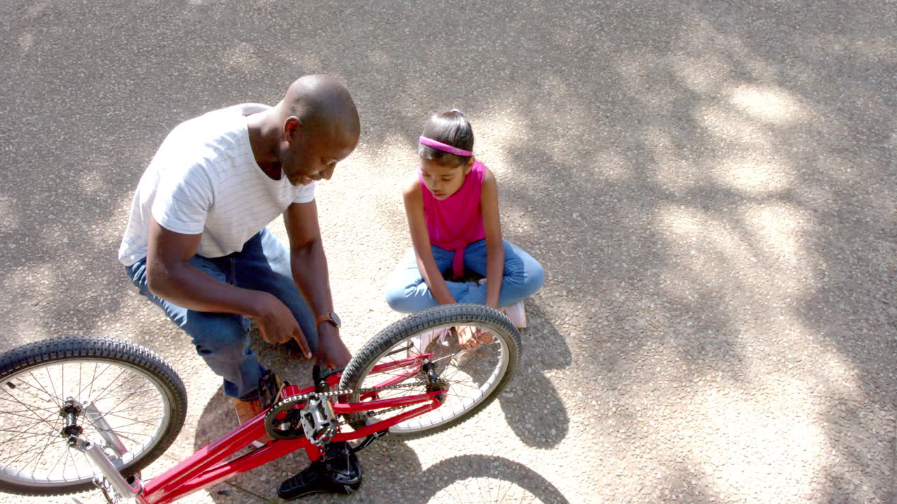 Fixing bicycle, African american man teaching child outdoor maintenance skills