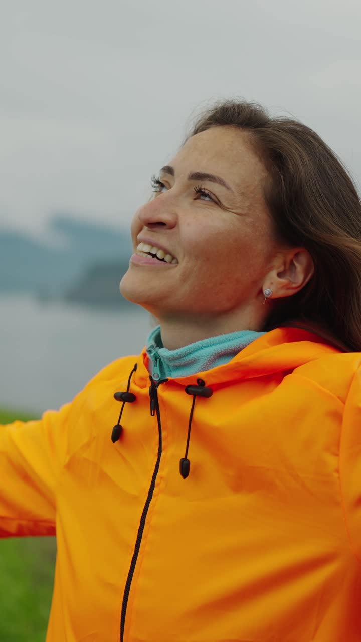 Joyful Woman in Orange Jacket Embracing Nature