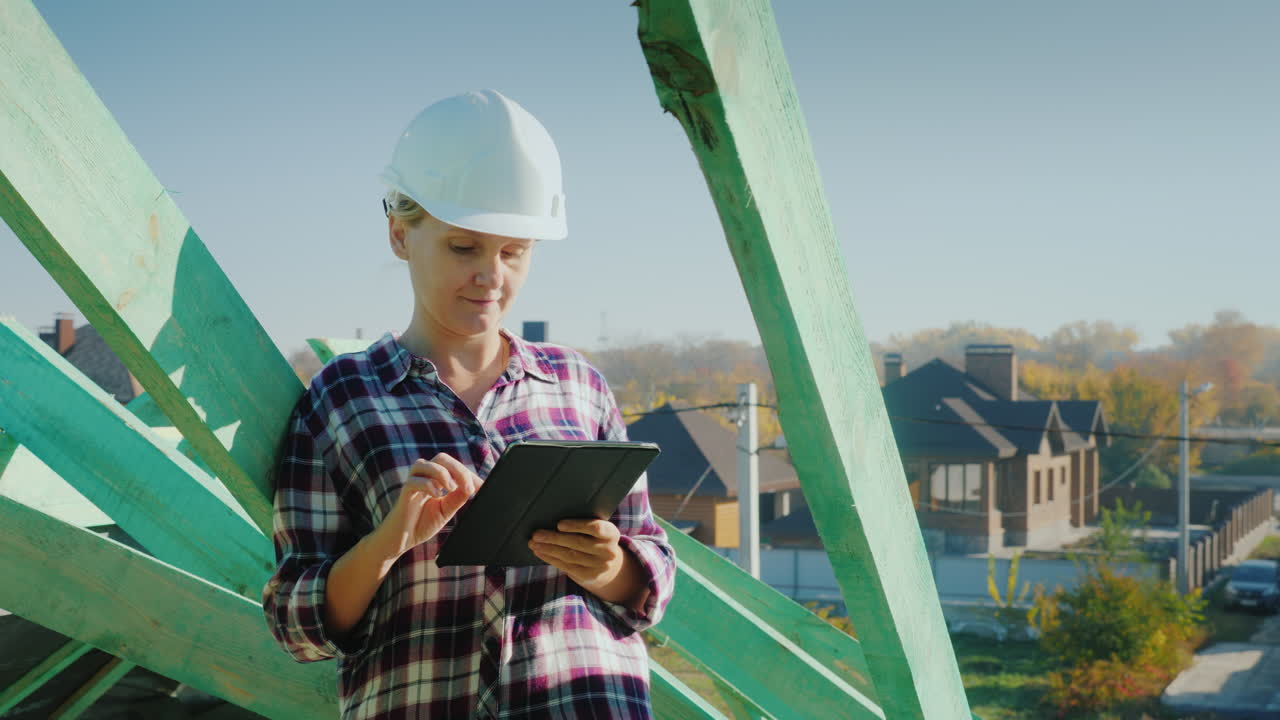 una arquitecta está trabajando con una tableta en el techo de una casa control técnico y de autor en