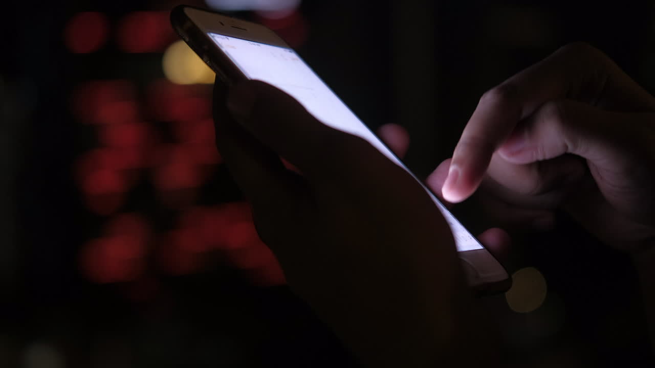 persona que utiliza un teléfono inteligente por la noche