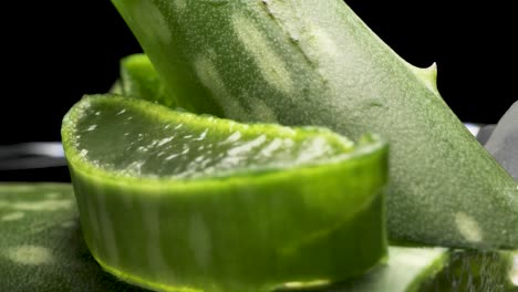 Fresh-Aloe-Vera-Sliced-on-the-black-background,-green-herb-concept-for-cosmetic-and-skincare-product-presentation,-round-smooth-motion