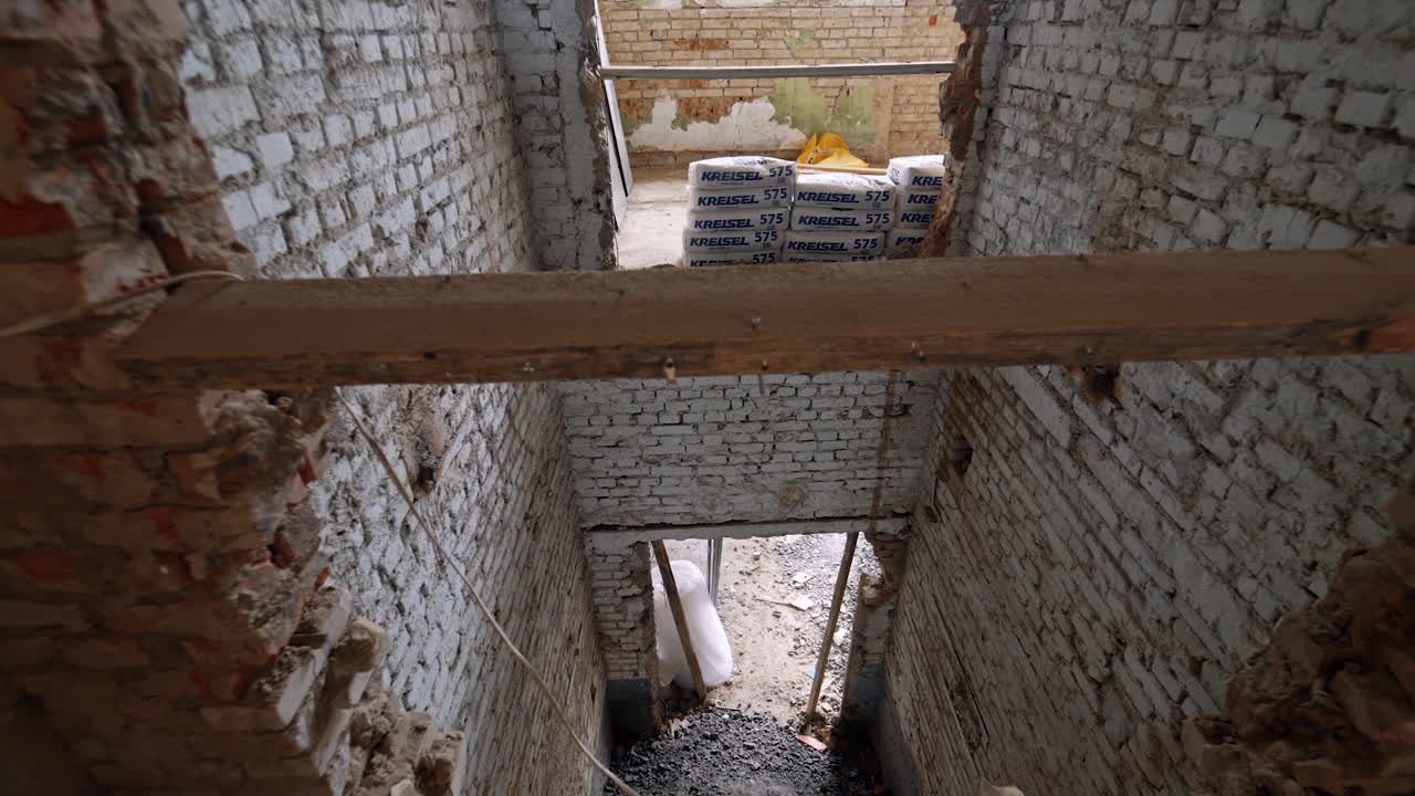 Interior of the old building with white brick walls. The sacks of materials for construction are stacked in a pile.
