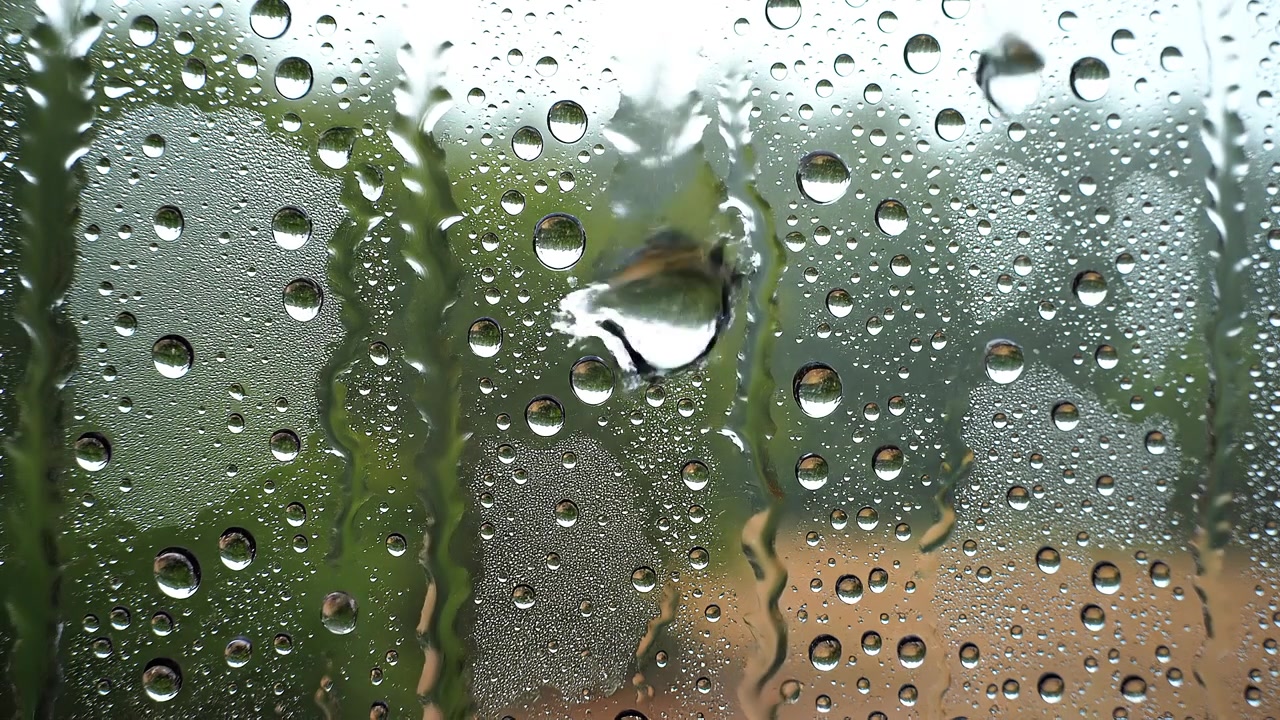 Gocce di pioggia fresche su superficie di vetro trasparente con sfondo bokeh