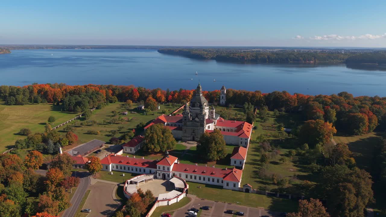 Aerial view of Pažaislis Monastery in Kaunas, Lithuania, during autumn, with colorful foliage and Kaunas Reservoir in the background. Historic Baroque complex surrounded by nature