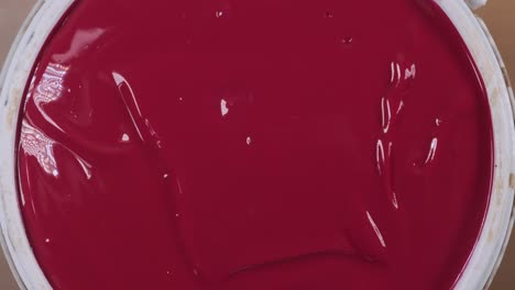 close up of woman opening plastic paint can to reveal red paint