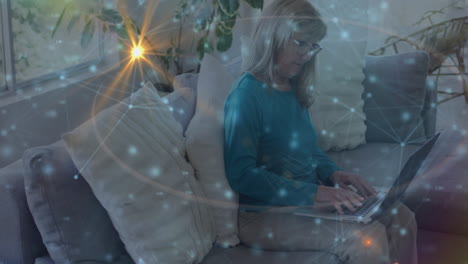 animación de la red de conexiones sobre una mujer caucásica anciana usando una computadora portátil