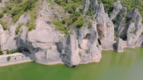 panning aerial footage of beautiful cliffs with road tunnels surrounded by lake