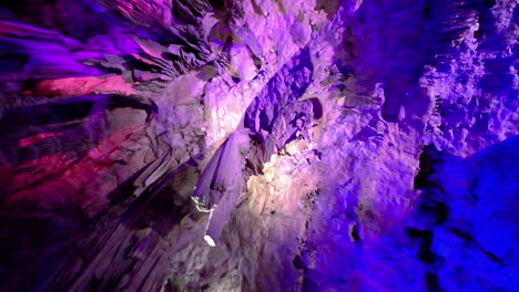 una foto suave de una cueva iluminada de colores en españa con personas que la visitan