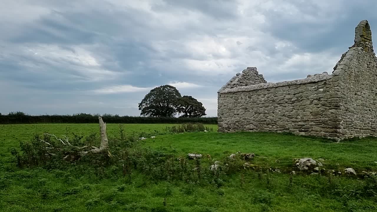las ruinas de capel iligwy en el campo rural de moelfre, anglesey, gales del norte, derecha panorámica lenta ranura