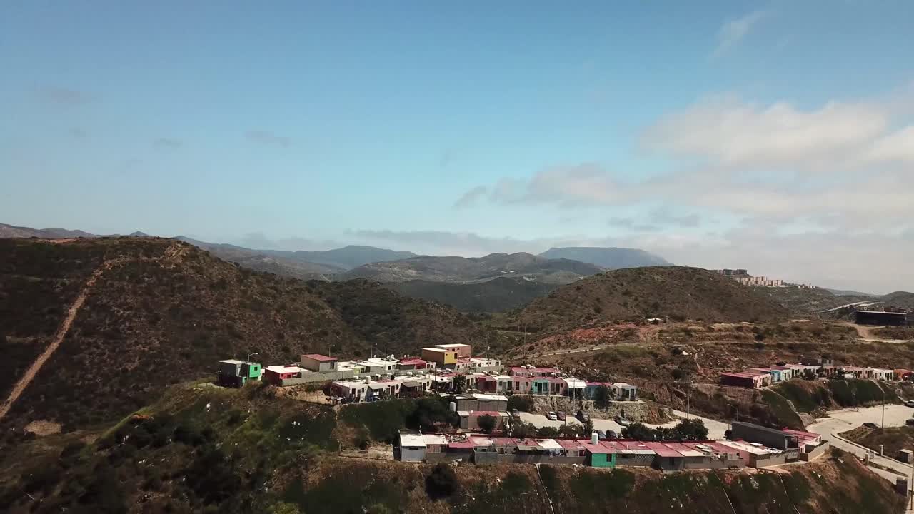 Drone footage of Haciendo Las Delicias, Baja, Mexico in the daytime. This shot is a wide angle of a smaller part of the community and layers of mountains.