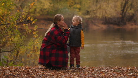 communication of mother and child at nature in forest woman and her little son are resting at coast of pond love and family
