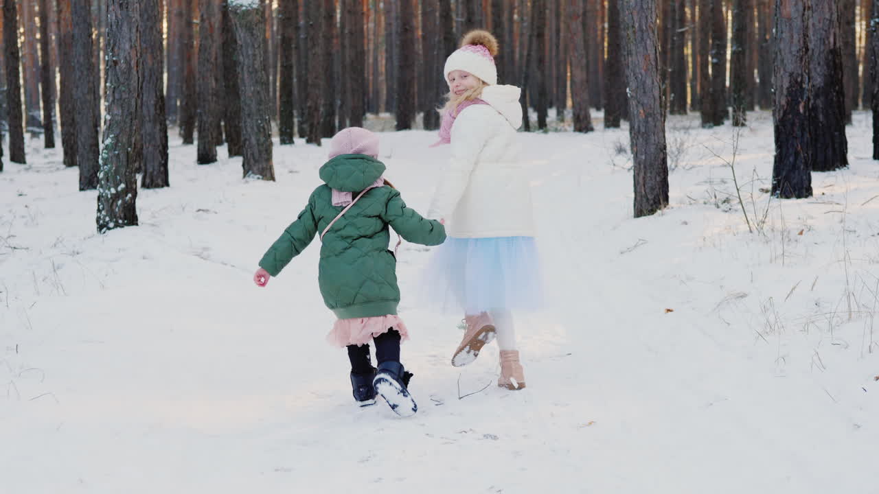 dos niñas despreocupadas corriendo por el bosque de invierno vista posterior