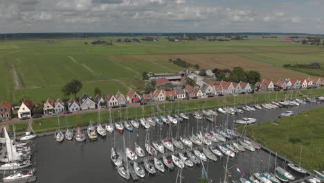 Panorámica-Aérea-Y-Rotación-Que-Muestra-La-Zona-Del-Puerto-Marítimo-Para-Embarcaciones-De-Recreo-Con-Casas-Típicas-Del-Pueblo-Holandés-De-Durgerdam-En-Durgerdammerdijk-Cerca-De-Amsterdam-En-Un-Día-Nublado