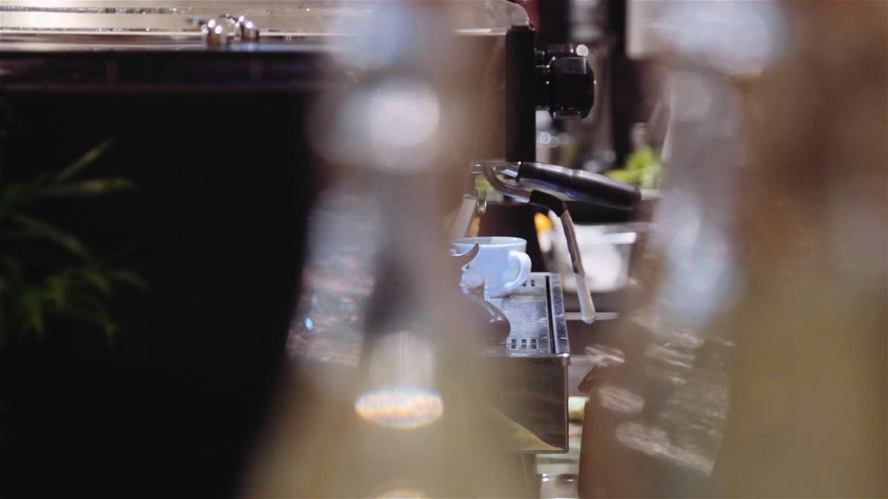 Barista's Hand In Glove Frothing Milk On A Coffee Machine