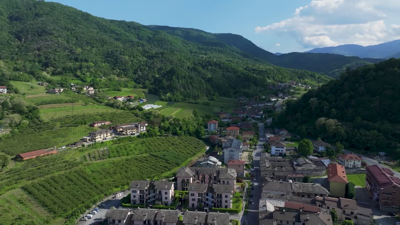 Stunning aerial drone footage captures beautiful resorts and houses nestled amidst majestic green mountains under a dramatic cloudy sky