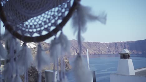 close up of a dreamcatcher to a wide shot of the beautiful coastline of santorini