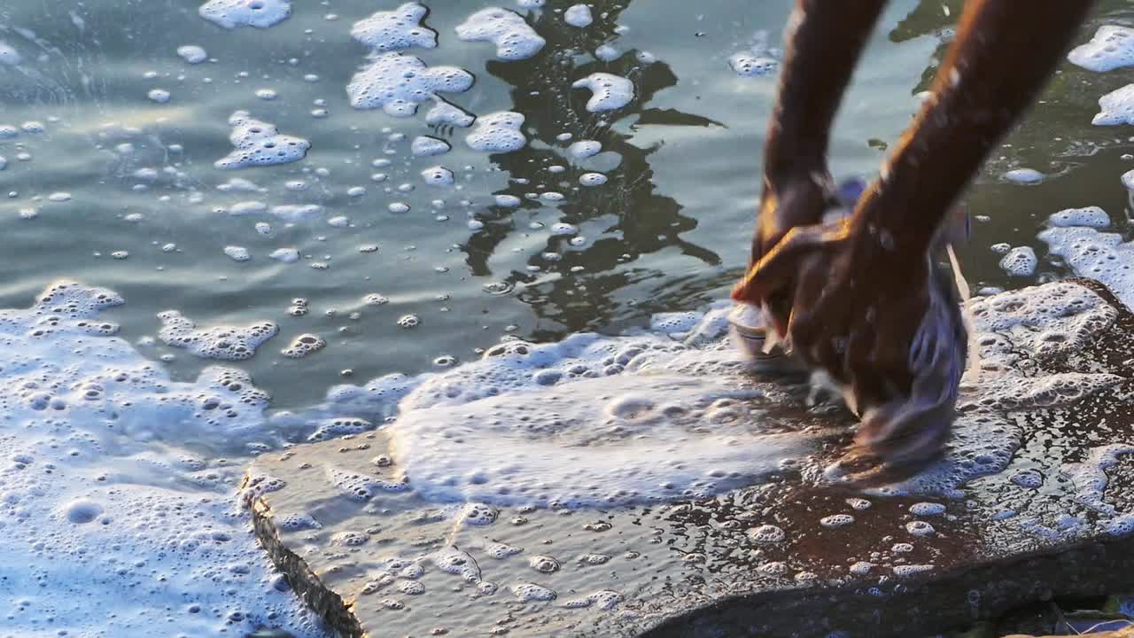 A local washing clothes on the river ganges in Varanasi City of India and causing Water Pollution - Slow motion