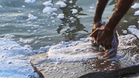 a local washing clothes on the river ganges in varanasi city of india and causing water pollution - slow motion