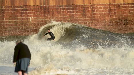 Aerial-surfer-catching-wave-off-the-lighthouse-peir-at-Roker-beach,-surfing-in-the-north-east-of-England