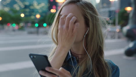 portrait of young attractive blonde woman wearing earphones listening to music smiling happy texting browsing using smartphone enjoying calm urban evening in city