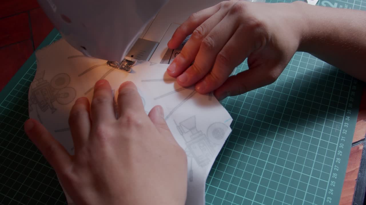 직물이 당겨지고 안내되는 것처럼 보이는 손과 재봉틀